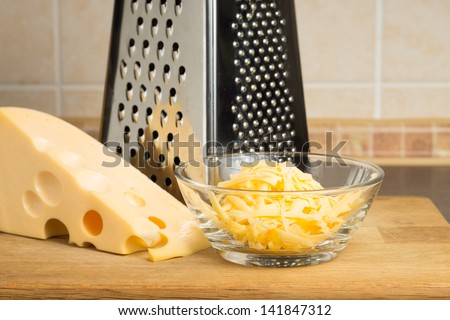 Grated cheese in Glass Bowl with Grater. Front view