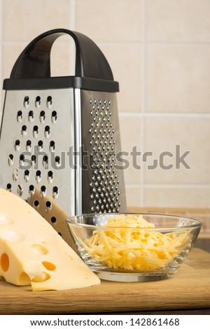 Grated Yellow Cheese with Grater at the kitchen table