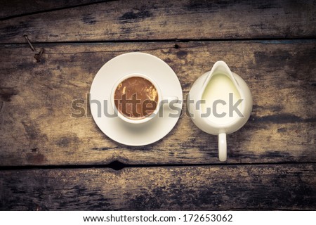 Coffee. Cup of Coffee with Milk Jug on Wood Background. Warm color toned