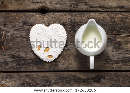 Milk Jug with big Gingerbread Cookies on old wood background. Heart Shape.