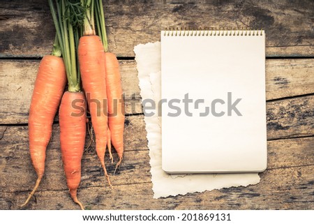 Warm color toned series of Vegetables with recipe book on wooden table. Old wood background. Menu background. Carrot