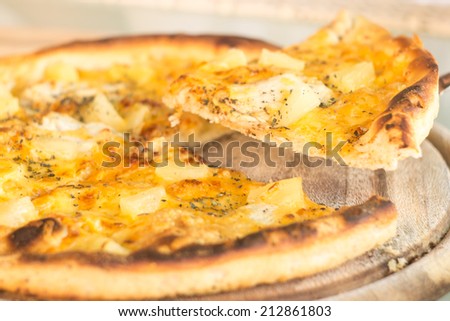 Baked cut pizza with pineapple and meat on wooden board. Selective focus image. Fast food meal time