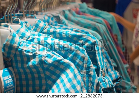 Various hipster shirts on hangers in store. Trendy clothes