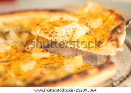 Baked cut pizza with pineapple and meat on wooden board. Selective focus image. Fast food meal time