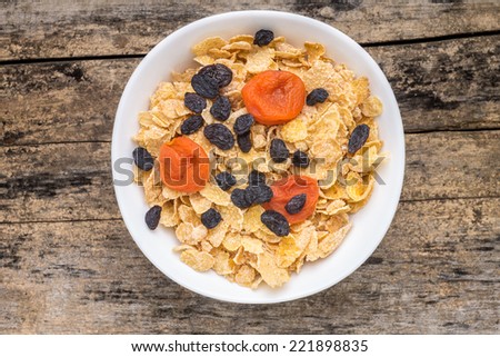 Corn flakes with dried fruits on wooden table. Healthy lifestyle background