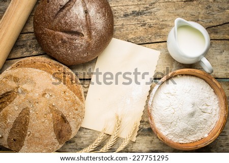 Bakery ingredients with fresh loaf of bread and blank paper card for recipe or menu.