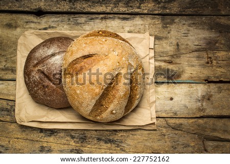 Loafs of bread on paper bag lying at wood background with copy space