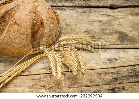 Bakery background. Fresh bread on wooden table with wheat ears.