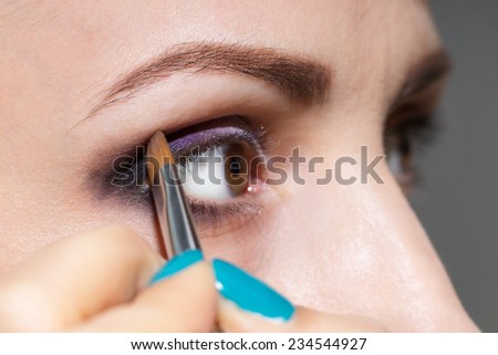 Make up woman applying eyeshadow powder with brush