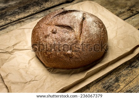 Loaf of rye bread on paper bag. Bakery background