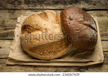 Loafs of different bread on paper bag at wooden background