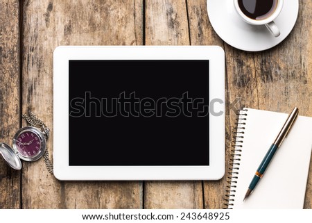 Remote workplace top view. Digital tablet PC with old clock, notebook and cup of coffee on wooden background.