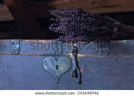 Old chest with heart shaped keyhole and bunch of dried herbs lies above