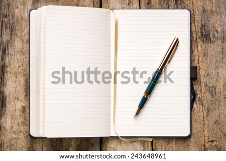 Opened empty notebook with retro fountain pen on wooden table. Writing background