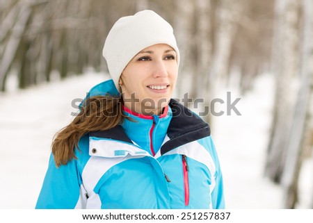 Cheerful young sport woman at winter outdoor activity. Smiling caucasian girl jogging in winter park
