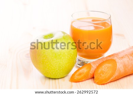 Glass of fresh carrot and apple juice on wooden table. Healthy eating menu background.