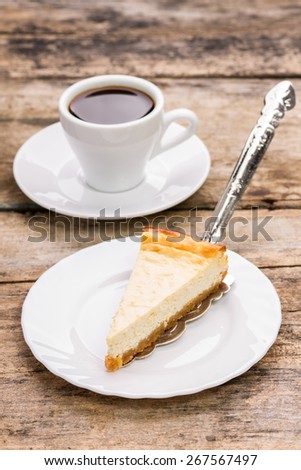 Slice of cheesecake on plate with cup of coffee on wooden table. Restaurant dessert menu background