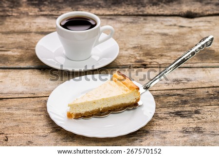 Cheesecake with cake server and cup of coffee on wooden table. Dessert menu background
