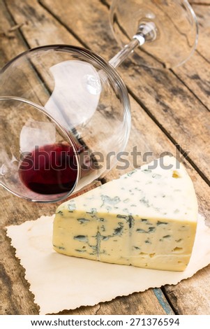 Blue cheese on vintage paper with overturned wineglass on wooden table. Restaurant wine list background.