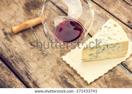 Blue cheese on wood background. Sort of mold cheese with wine glass and corkscrew