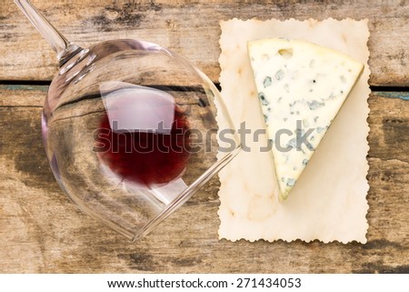Blue cheese with overturned glass of red wine on vintage paper. Restaurant wine list background. Top view image