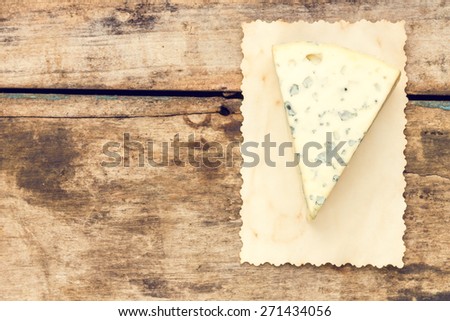 Blue cheese background with copy space. Piece of cheese with mold on wooden table