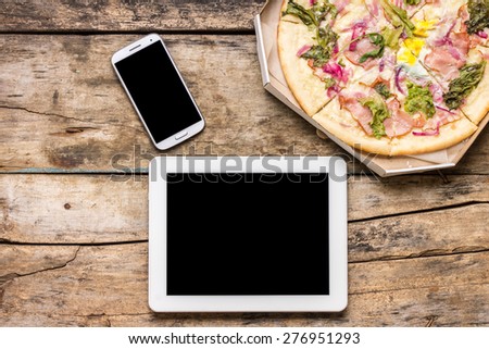 Business lunch mock up. Fast on-line delivery pizza. Top view image of Tablet PC, smartphone and Pizza