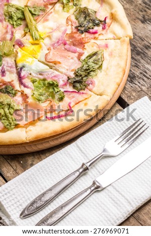Pizza with bacon and herbs with fork and knife. Fast food eating background