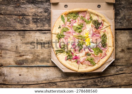 Restaurant menu and recipe background. Gourmet pizza in box on wooden table with copy space
