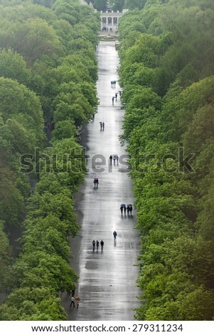 Alley of City park after rain. People walks on parkway. Aerial view image of resting people