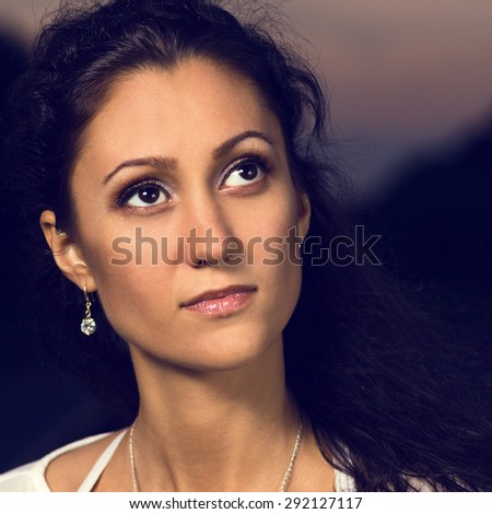 Pretty young woman looking aside. Evening portrait of sun-tanned girl at outdoor. Toned image