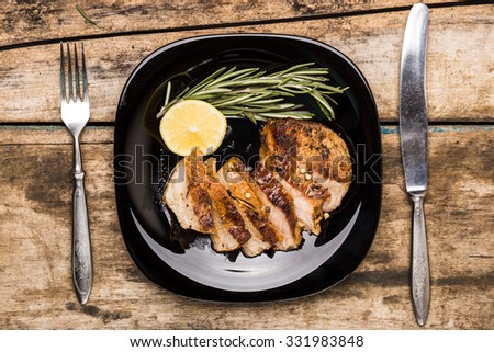 Top view image of sliced grill beefsteak served with lemon and rosemary on wooden table. Restaurant steak house menu or recipe background
