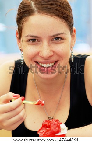 young caucasian  brunette woman portrait in cafe eating ice-cream with spoon in mouth