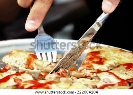 eating pizza closeup with knife and fork