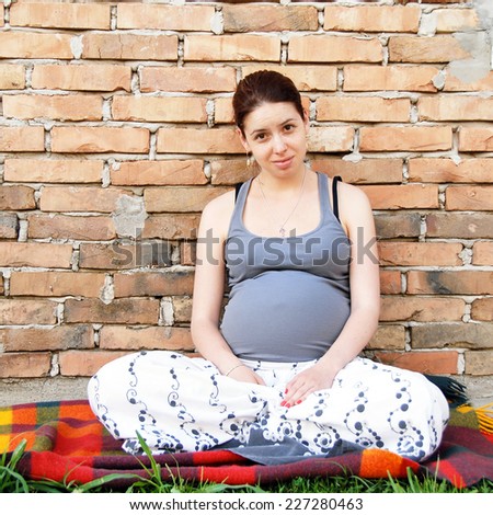 young caucasian pregnant woman sitting in lotus posture