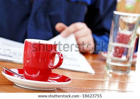 man reading newspaper drinking coffee and water