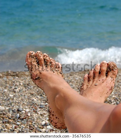 stock photo : woman feet in tiny rocks on pebble beach