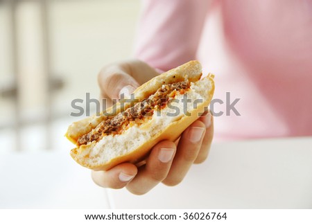 half eaten hamburger in teen girl hand closeup