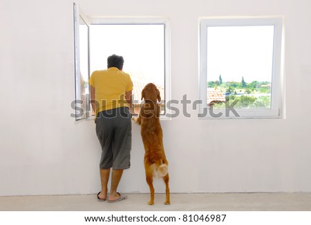 man and his dog looking through window back view