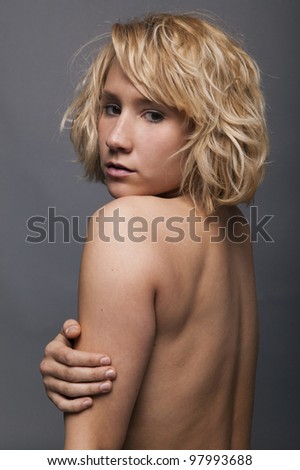 Young blonde sporty woman showing her back on gray isolated background