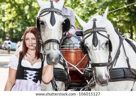 Woman in dirndl with a horse and wedding carriage