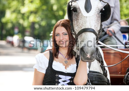 Woman in dirndl with a horse and wedding carriage