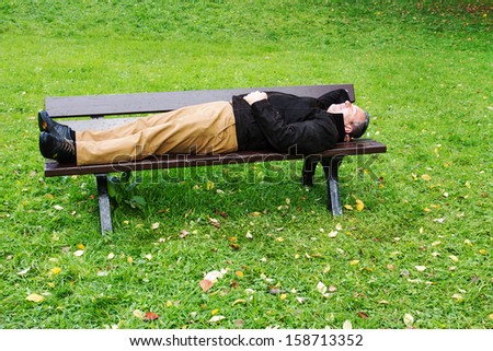 Man enjoys the autumn sun on the park bench