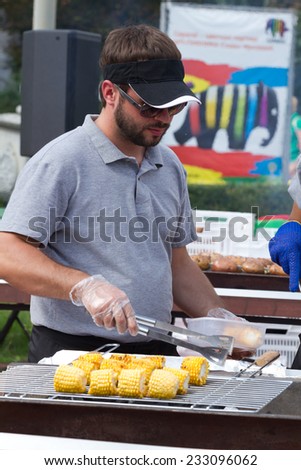 KIEV, UKRAINE - AUGUST 08, 2014:A man cooking sweet corn on a grill on a beer festival in Kyiv, Ukraine