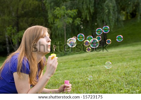 beautiful girl makes soap bubble on a grass