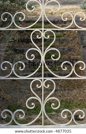 Wrought Iron Gate - Decorative gate opens on stone stairs leading to an abandoned French seaside villa.