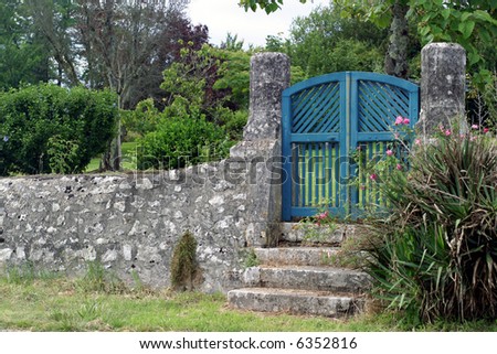 Blue Gate - a few steps lead up to a wooden garden gate framed by two old limestone pillars.