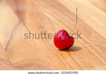 Single cherry on wooden table