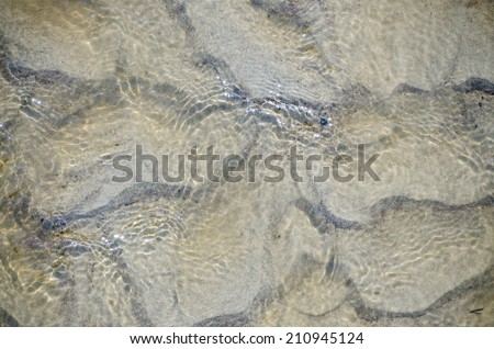 Refreshing blue tinted clear water shallow water creating ripples in the sand beneath