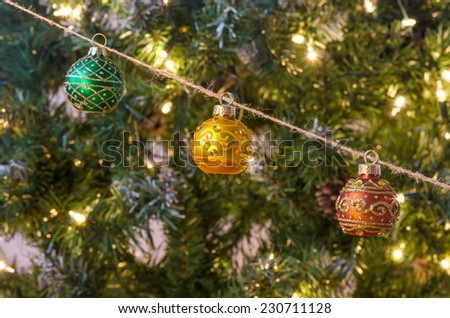 Traditional decorative Christmas balls hanging from rustic twine in front of Christmas tree